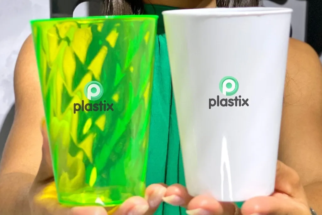 Dois copos personalizados com a marca Plastix, um verde translúcido e um branco